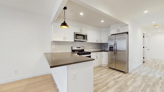 800 5th Ave Unit 1A, New York City, NY 11232 - kitchen with appliances with stainless steel finishes, dark countertops, a peninsula, light wood finished floors, and tasteful backsplash