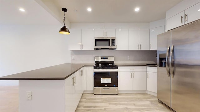 kitchen with a peninsula, dark countertops, white cabinets, and stainless steel appliances