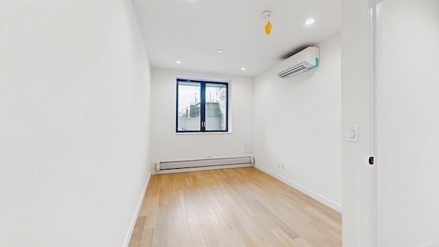 spare room with baseboards, light wood-style flooring, a baseboard radiator, and a wall unit AC