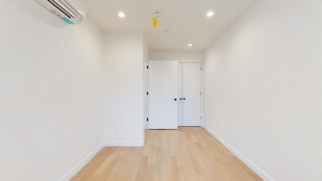 hallway featuring recessed lighting, light wood-style floors, an AC wall unit, and baseboards