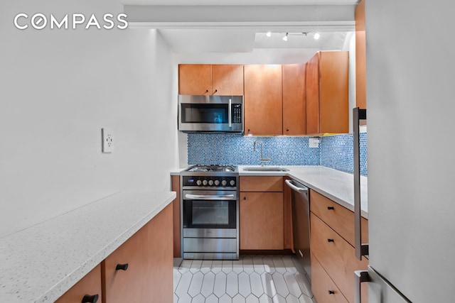 kitchen featuring stainless steel appliances, a sink, light countertops, backsplash, and light tile patterned floors