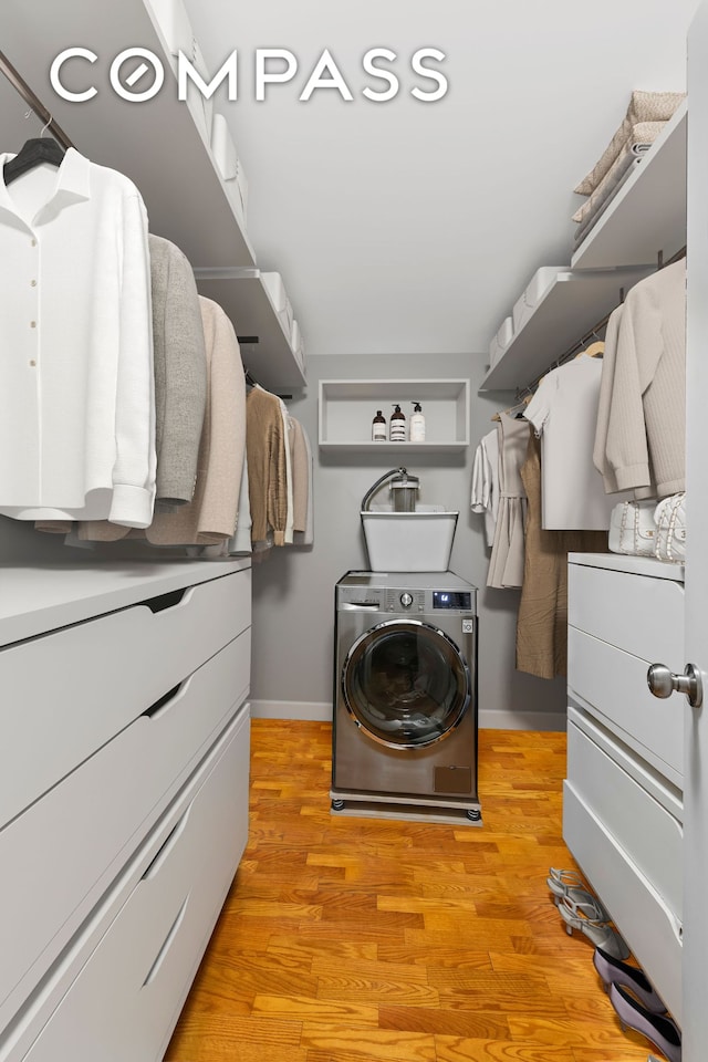 clothes washing area with washer / dryer, baseboards, and light wood-type flooring