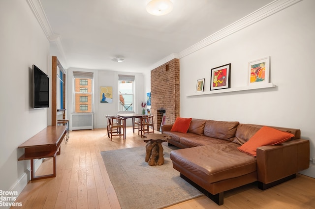 living room featuring crown molding, a brick fireplace, light wood-type flooring, baseboards, and radiator