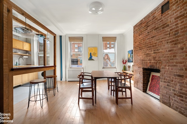 dining area with crown molding, a fireplace, and light wood-style flooring