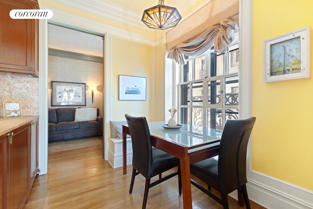 dining room featuring light wood-type flooring, baseboards, crown molding, and a chandelier