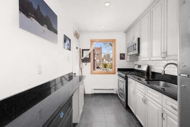 kitchen featuring tasteful backsplash, dark tile patterned floors, appliances with stainless steel finishes, a baseboard radiator, and a sink