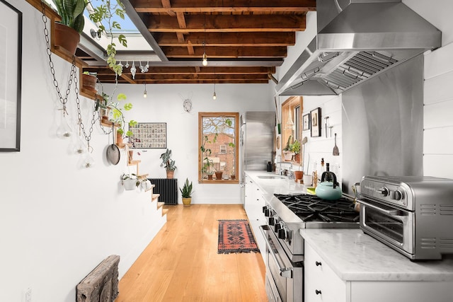 kitchen with light wood-style floors, ventilation hood, white cabinetry, high end stainless steel range oven, and a toaster