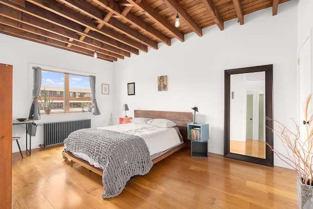 bedroom with light wood-style flooring, wood ceiling, radiator, and beam ceiling
