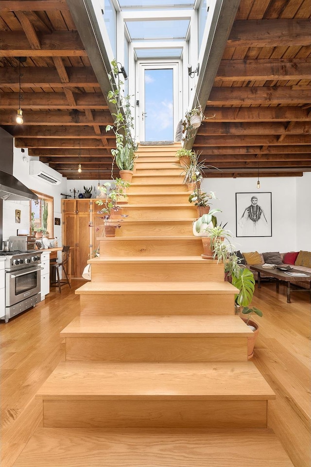 stairway featuring beamed ceiling, wooden ceiling, and wood finished floors