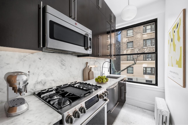 kitchen with appliances with stainless steel finishes, a sink, dark cabinets, radiator, and decorative backsplash