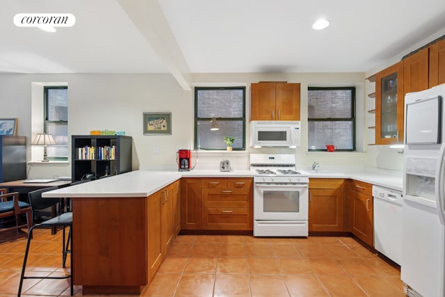 kitchen featuring white appliances, a peninsula, a sink, light tile patterned floors, and recessed lighting