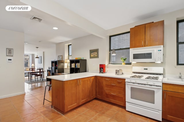 kitchen with white appliances, a peninsula, brown cabinetry, light tile patterned flooring, and recessed lighting