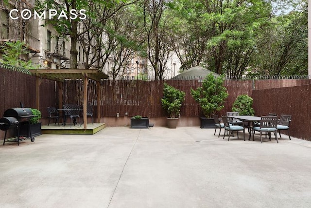 view of patio with a fenced backyard, outdoor dining space, a wooden deck, and area for grilling