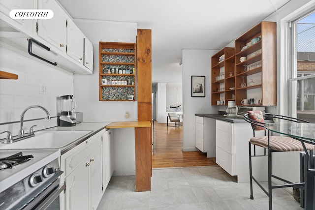 789 W End Ave Unit Ph6, New York City, NY 10025 - kitchen featuring a sink, open shelves, white cabinetry, and stainless steel range with gas stovetop