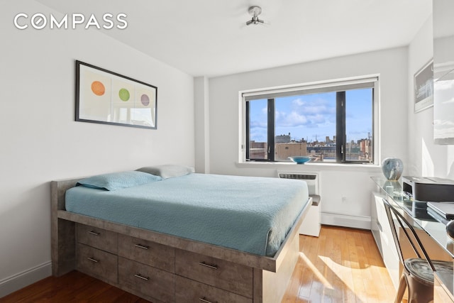 456 W 167th St Unit 7C, New York City, NY 10032 - bedroom with light wood-style flooring, baseboards, and an AC wall unit