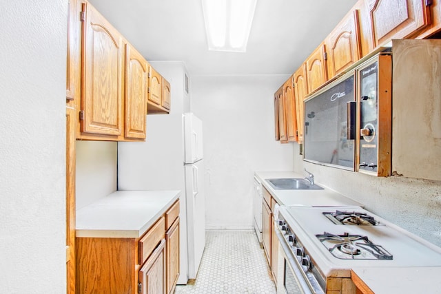 kitchen featuring light floors, a sink, white appliances, and light countertops