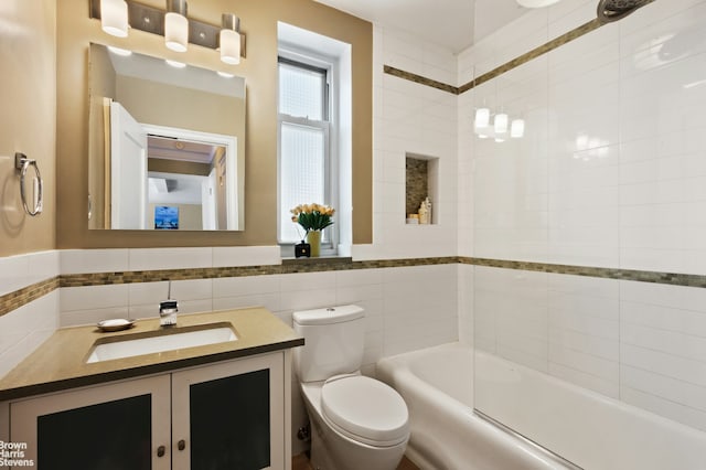 full bathroom featuring shower / tub combination, vanity, toilet, a wainscoted wall, and tile walls