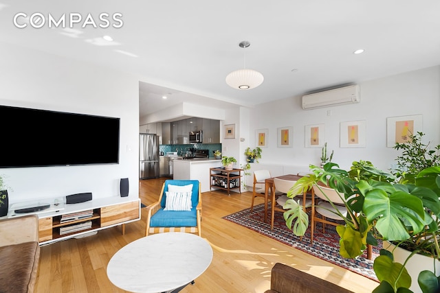 living area with a wall unit AC, light wood finished floors, and recessed lighting