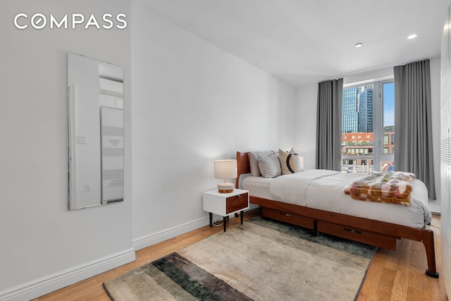 bedroom with wood finished floors, baseboards, and recessed lighting