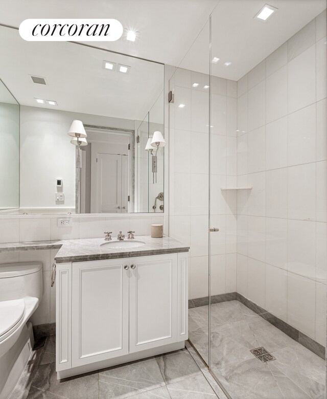 40 E 72nd St Unit 5, New York City, NY 10021 - full bath featuring marble finish flooring, toilet, vanity, a stall shower, and tile walls