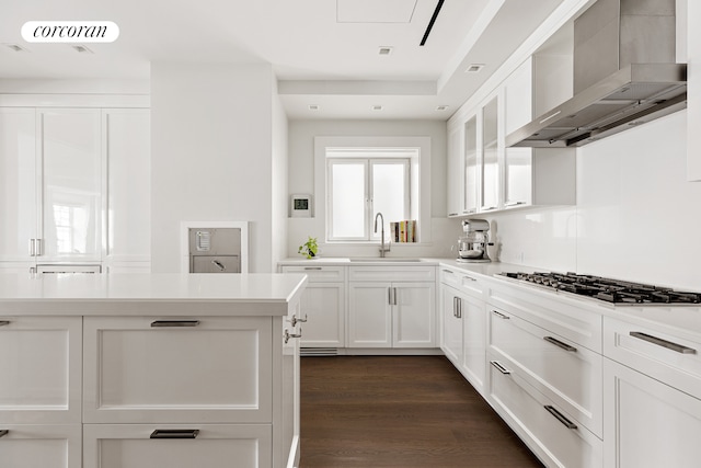 40 E 72nd St Unit 5, New York City, NY 10021 - kitchen featuring wall chimney range hood, a sink, gas cooktop, light countertops, and white cabinets