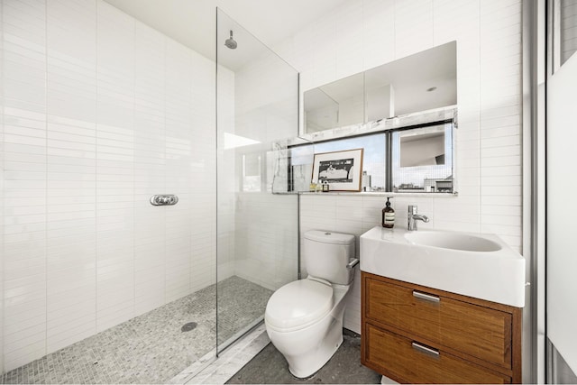 bathroom featuring toilet, a walk in shower, tile walls, and vanity