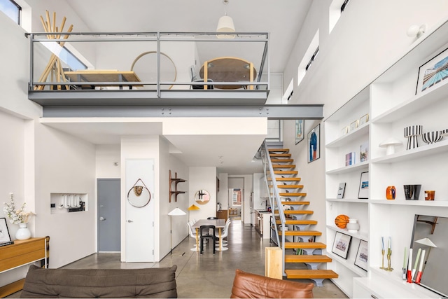 foyer featuring finished concrete flooring, a towering ceiling, and stairway