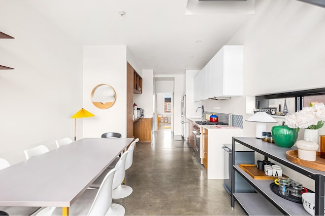 kitchen with stainless steel appliances, white cabinetry, concrete flooring, and light countertops