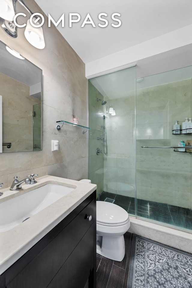 full bath with vanity, toilet, tile walls, and a stall shower