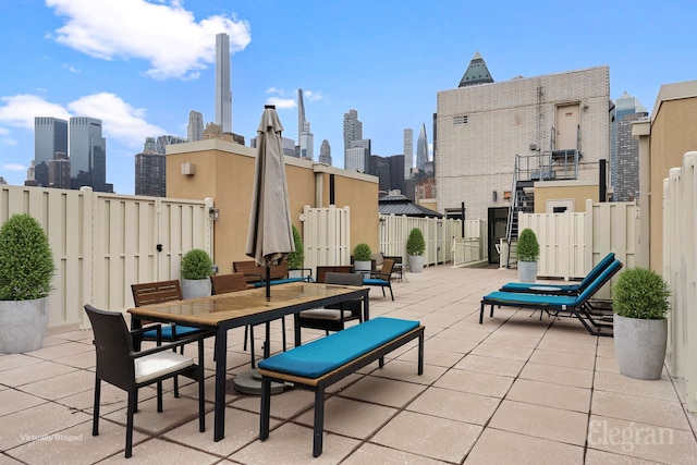 view of patio featuring outdoor dining space, a view of city, and fence