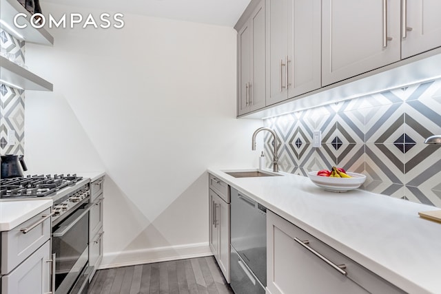 250 W 15th St Unit 3C, New York City, NY 10011 - kitchen featuring appliances with stainless steel finishes, a sink, backsplash, gray cabinets, and dark wood finished floors