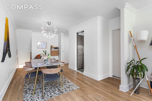 dining room featuring light wood finished floors, a chandelier, baseboards, and ornamental molding