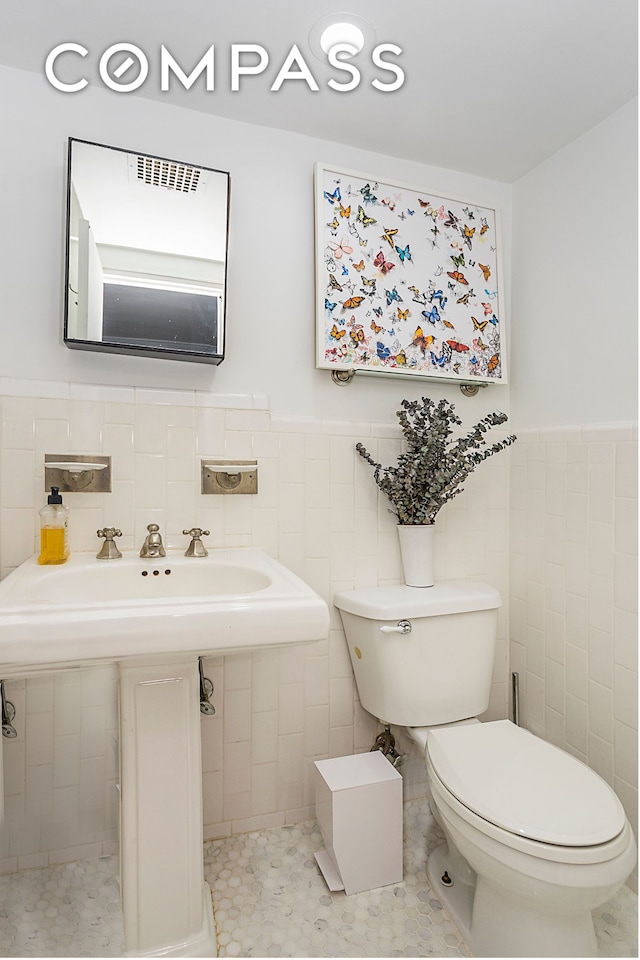 250 W 15th St Unit 3C, New York City, NY 10011 - half bathroom with toilet, tile walls, wainscoting, and tile patterned flooring