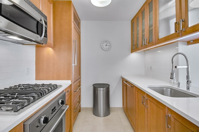 205 E 85th St Unit 7-B, New York City, NY 10028 - kitchen featuring appliances with stainless steel finishes, a sink, brown cabinets, and backsplash