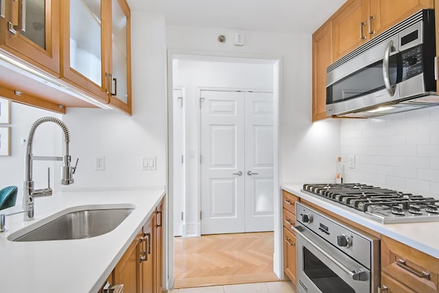 205 E 85th St Unit 7-B, New York City, NY 10028 - kitchen with stainless steel appliances, a sink, brown cabinets, decorative backsplash, and light countertops