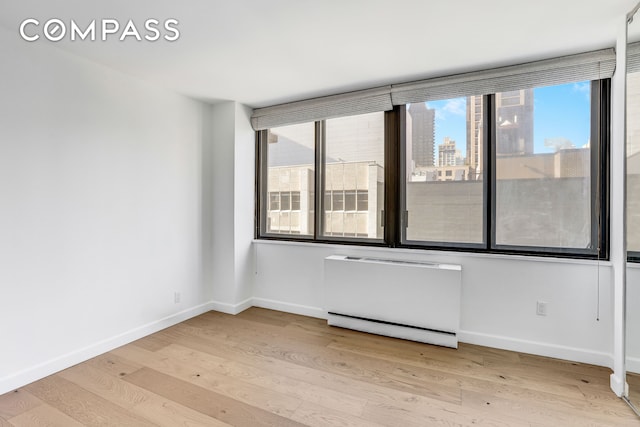 empty room with baseboards and light wood-type flooring