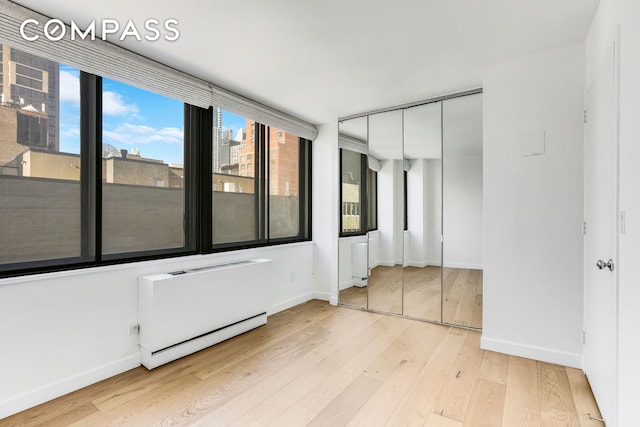 unfurnished bedroom featuring light wood-type flooring, baseboards, and a closet