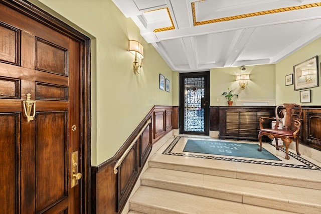 entrance foyer with a wainscoted wall, coffered ceiling, and beam ceiling
