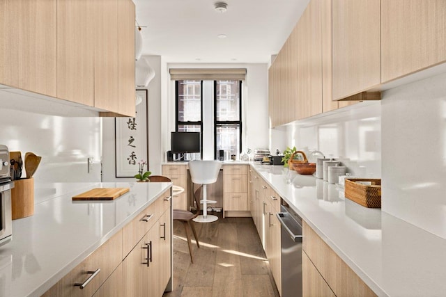 kitchen featuring light brown cabinetry, modern cabinets, stainless steel dishwasher, dark wood-style flooring, and light countertops