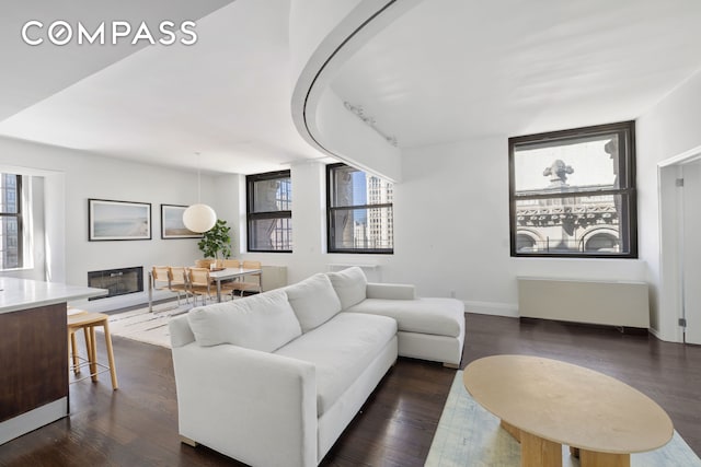 150 Nassau St Unit 18Ab, New York City, NY 10038 - living area featuring dark wood-style flooring, baseboards, and a glass covered fireplace