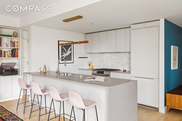 111 Montgomery St Unit 7M, New York City, NY 11225 - kitchen featuring high end stainless steel range, white cabinets, backsplash, and a kitchen breakfast bar