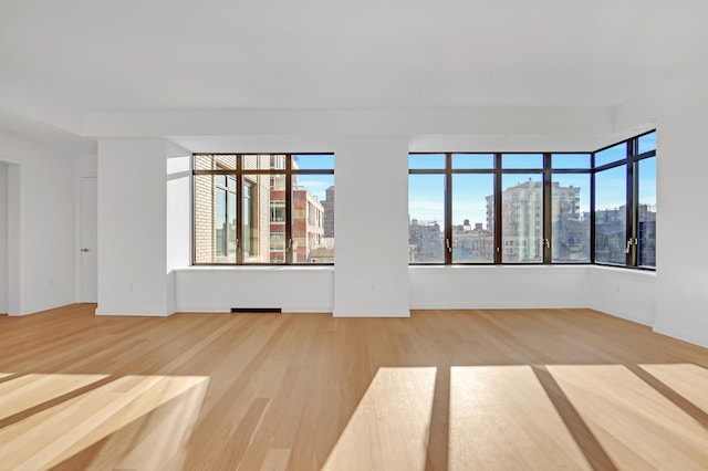 empty room featuring baseboards, a city view, and light wood finished floors