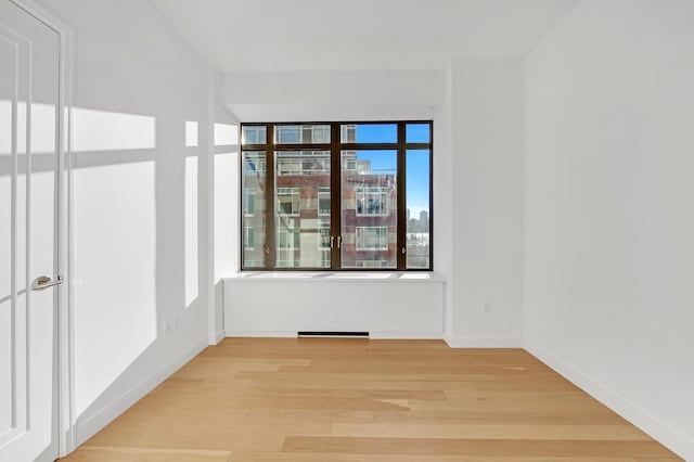 unfurnished room featuring baseboards and light wood finished floors