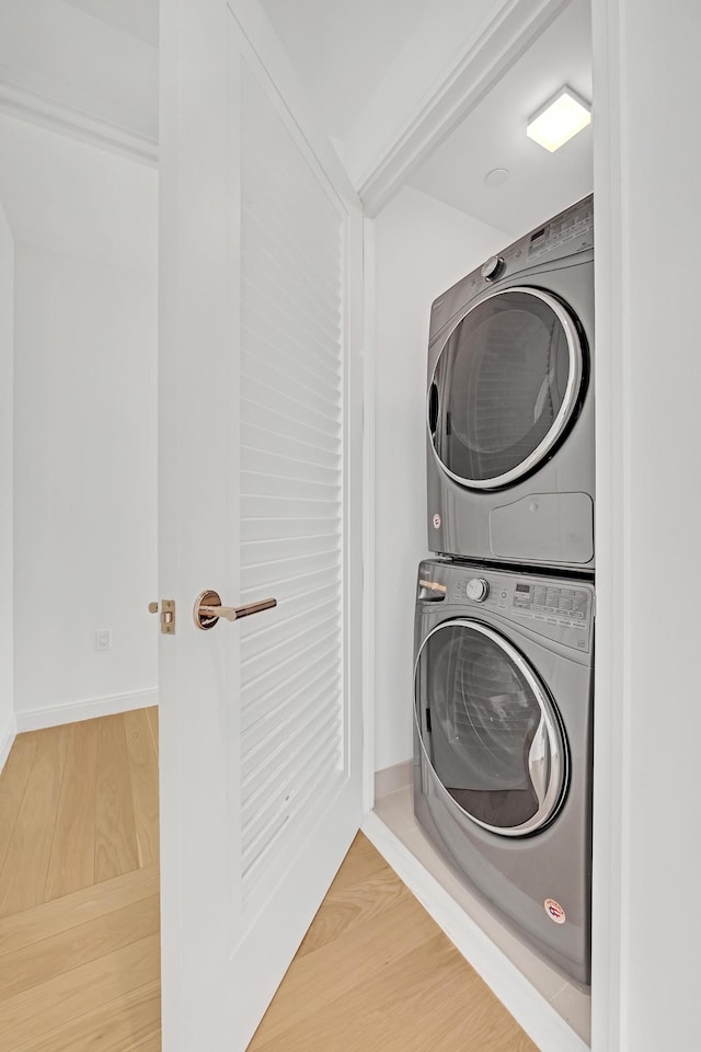 269 W 87th St Unit 14-A, New York City, NY 10024 - clothes washing area featuring baseboards, stacked washer and clothes dryer, wood finished floors, and laundry area