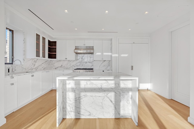 269 W 87th St Unit 14-A, New York City, NY 10024 - kitchen with light wood finished floors, stove, backsplash, white cabinetry, and under cabinet range hood