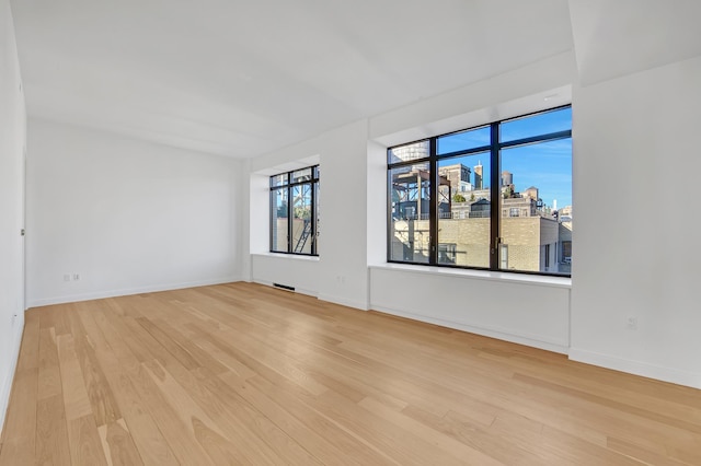 spare room with baseboards, visible vents, and light wood-style flooring