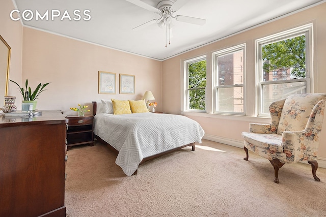 carpeted bedroom with a ceiling fan, ornamental molding, and baseboards