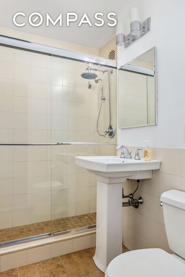 full bath featuring toilet, a shower stall, tile patterned floors, and tile walls
