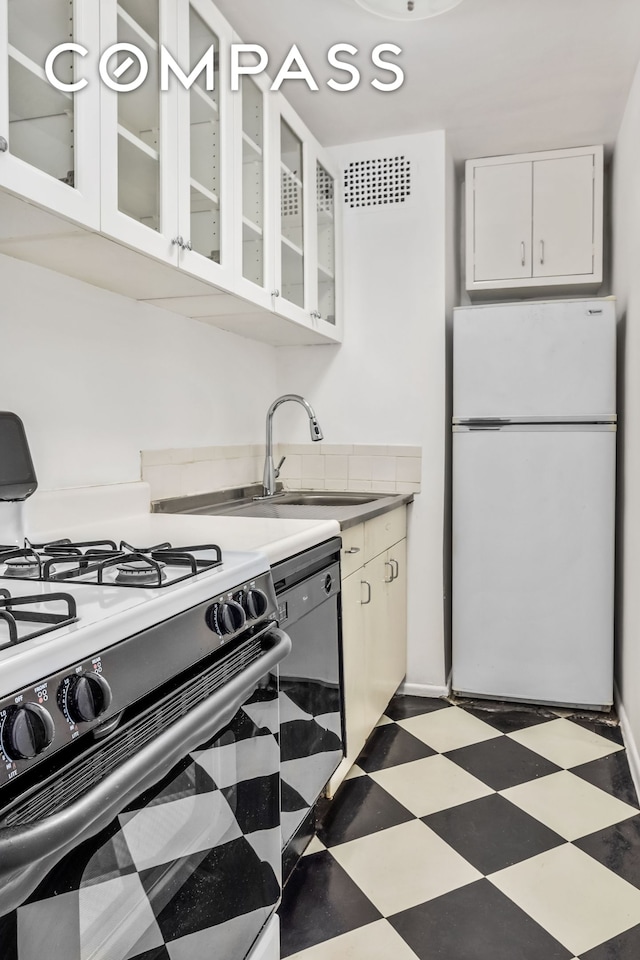 kitchen featuring range with gas cooktop, freestanding refrigerator, tile patterned floors, white cabinets, and glass insert cabinets