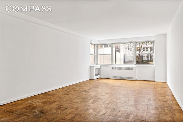 spare room featuring radiator and baseboards